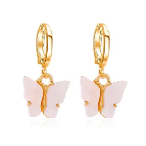 Gedetailleerd overzicht van gouden creoolse oorbellen met delicate roze acryl vlinderhangers.