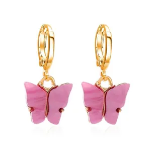 Gedetailleerde close-up van de elegante roze acryl vlinder hanger oorbellen met gouden hoepels.