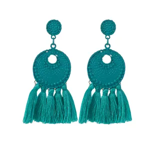 Detailopname van elegante turquoise kwastoorsieraden met retro metalen noppen en bungelende draden.