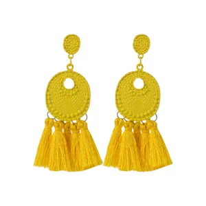 Gele kwast oorbellen detail opname, vintage metaal knop met lange textiel franjes.