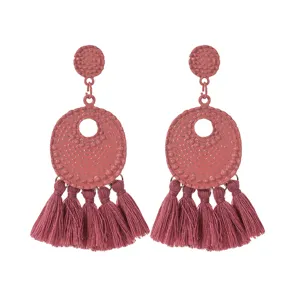 Gedetailleerde opname van vintage roze metalen en kwast oorbellen voor dames mode.