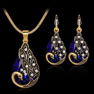 Elegante set di collana e orecchini con pavone, pietre preziose blu e strass brillanti per donna.
