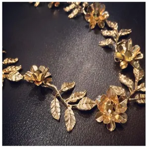 Nahaufnahme des goldenen Blumen- und Blätter-Haarbandes aus Legierung mit feinen Details.