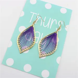 Primer plano de pendientes geométricos calados hechos a mano con hilo morado y dorado.