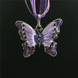 Detailopname van de paarse geëmailleerde vlinderhanger met sprankelende strass-steentjes.