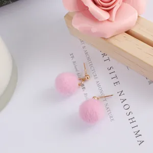 Leuke roze pluche pompon oorbellen detailopname, zachte bal met gouden stekker.