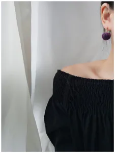 Close-up detailopname van een schattige paarse pluche pom-pom oorbel met zachte textuur