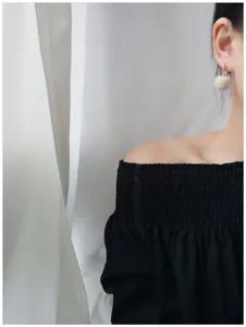 Close-up detail van schattige pluizige pompon oorbellen in het wit, elegante winterstijl.