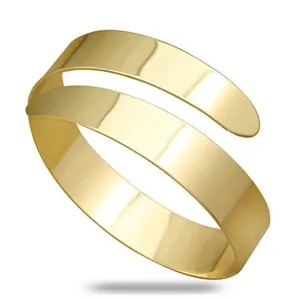 Minimalistische gouden metalen open armband manchet, glad gepolijst punk stijl sieraden detail.