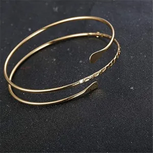 Dettaglio bracciale rigido aperto dorato a più giri, accessorio di gioielleria moda.