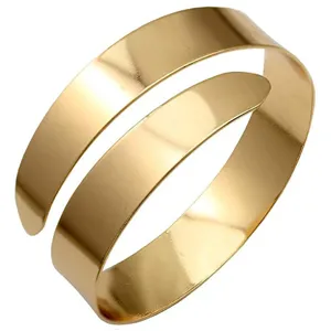 Close-up detail van de minimalistische gouden metalen manchet armbband met glad afgewerkt.
