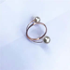 Dettaglio portatovaglioli di perle, elegante design a spirale in oro rosa per tavola e feste.