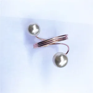 Dettaglio ravvicinato del portatovagliolo a molla in oro rosa con eleganti perle.