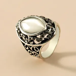 Detail van een vintage zilveren ring met een witte kattenoogsteen en zwarte accenten.