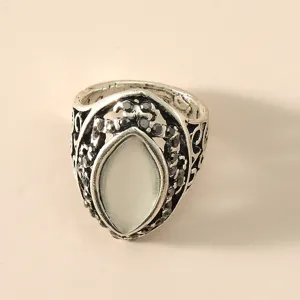 Vintage zilverkleurige opengewerkte ring met een centrale witte kattenoogsteen en zwarte stenen.