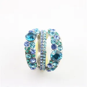 Detail van een meerlagige ring met blauwe en groene kristallen en strass-steentjes.
