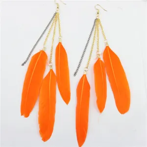 Gedetailleerd overzicht van oranje veren kwast oorbellen met metalen kettingen voor boho stijl.