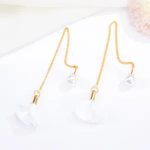 Detailed view of gold-plated long chain earrings featuring white fabric flower petals and pearls.