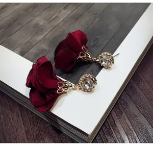 Close-up detail shot of elegant dark red fabric rose flower earrings featuring sparkly rhinestone studs.