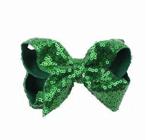 Detailopname van de sprankelende groene pailletten strik haarspeld met glanzende textuur.