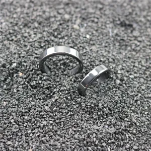 Close-up detail of simple dark magnetic rings displayed on textured mineral stone background.