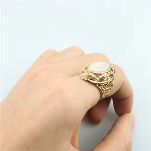 Detailopname van de vintage vergulde ring met opengewerkte takken, witte kattenoogsteen en fijne strass.
