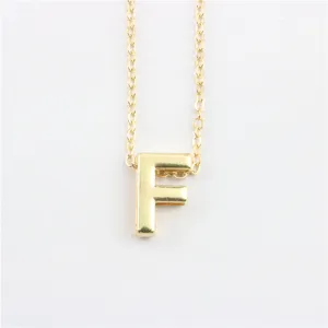 Detailopname van een minimalistische vergulde letter F hanger aan een fijne ketting.