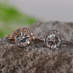Detailopname van strass ringen in goud en zilverkleur op een getextureerde stenen ondergrond.