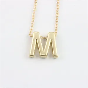 Close-up detail van de gouden letter M hanger ketting, met fijne metaaltextuur en fijne ketting.
