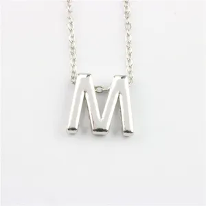 Close-up detail van zilveren letter M hanger ketting, elegante accessoire schakelketting.