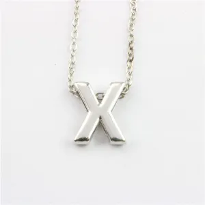 Detail van zilveren letter X hanger ketting, minimalistische metalen alfabet bedel close up