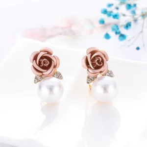 Detailopname van elegante rozenbloem oorknopjes met fonkelende strass-steentjes en parels.