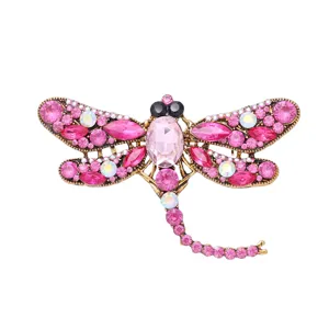 Gedetailleerde close-up van een sprankelende roze strass libel broche in vintage goud.