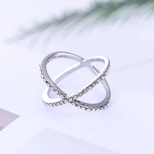 Prachtige zilveren kruisring met sprankelende strass-steentjes in een hol geometrisch detail.