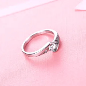 Detailopname van een delicate zilveren ring met een sprankelende steen en zirkonia.