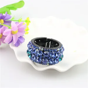 Close-up detail view of the sparkling blue rhinestone round hair clip on white dish display.