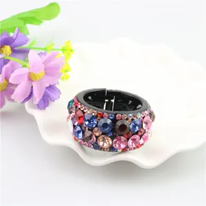Close-up detail of a circular rhinestone ponytail holder hair clip with colorful gems.