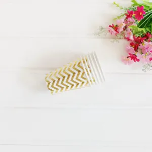 Gold chevron paper cups detail shot with flowers on white wood table, party disposable cup.