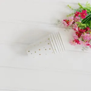 Detail shot of disposable paper cups with gold foil stars, placed near decorative flowers.