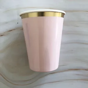 Close-up view of a pink disposable paper cup featuring an elegant gold rim design.