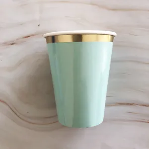 Detail shot of the mint green disposable paper cup with shiny metallic gold rim finish.
