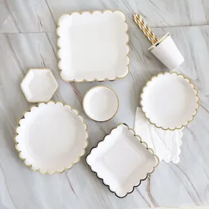 Vista dettagliata di piatti di carta usa e getta, bicchieri e cannucce bianchi e oro per feste.