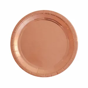 Gros plan d'une assiette en carton or rose avec bord gaufré et surface brillante.
