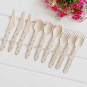 Detailed close-up of disposable wooden cutlery with polka dots, arranged on white slatted wood.
