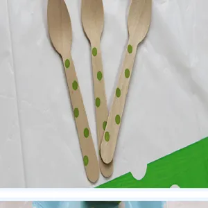 Detailed view of disposable wooden spoons with cute green polka dot patterns for desserts.