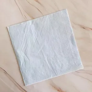 Close-up detail of a clean white paper napkin with embossed border texture on tabletop.