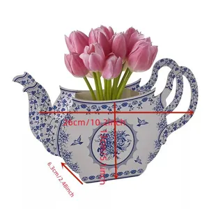 Detail view of blue and white porcelain teapot paper vase with pink tulips for table decor.