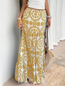 Close-up detail of the bohemian long skirt with intricate yellow medallion print, resort style.