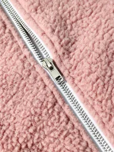 Close-up detail of soft pink fluffy fleece fabric and metal zipper closure for outerwear.