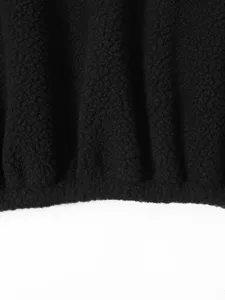 Close-up detail of black sherpa fleece jacket fabric texture, soft warm winter outerwear.
